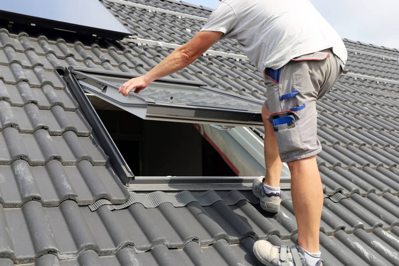Artisan sur une toiture entrain de vérifier l'installation d'une fenêtre de toit